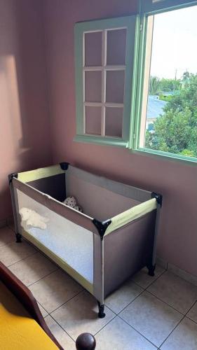 a crib in a corner of a room with a window at Haut de Villa T3, convivial à la campagne in Saint-Joseph