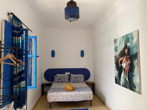 a bedroom with a bed and a painting on the wall at Riad Safi médina in Safi