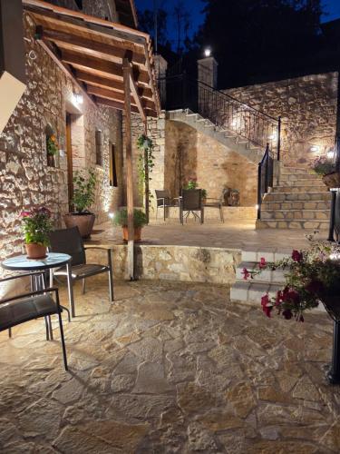 a stone patio with a table and chairs at night at MELATO HOUSES in Valtessiniko 