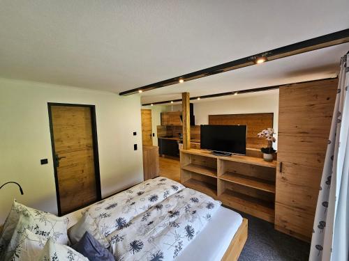 a bedroom with a bed and a flat screen tv at Haus Enzian Apartments in Kartitsch