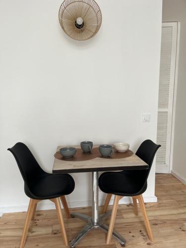 a table with two chairs and a table with bowls on it at Renote - Concept Appart Hôtel in Lannion