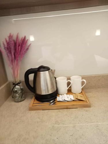 a coffee pot and two cups on a wooden tray at Novotel Manila Residence Hotel by Jolly Luxe Suites at Acqua in Manila