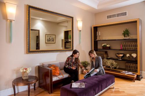 Due donne in piedi in un soggiorno con un divano viola di Tridente Suites a Roma