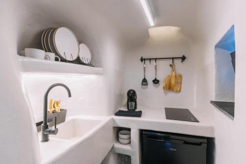 a small white bathroom with a sink and a counter at Noir Cave Villa with private Jacuzzi and Sunset Terrace in Pirgos