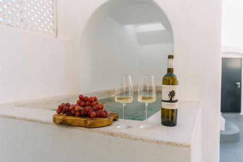 a bottle of wine and two wine glasses on a counter at Noir Cave Villa with private Jacuzzi and Sunset Terrace in Pirgos