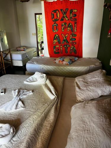a room with two beds and a red pillow at Eden One in Ilhéus