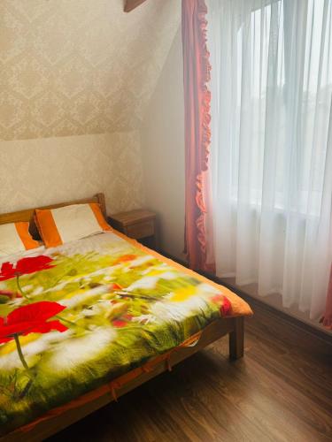 a bedroom with a bed with a flower blanket on it at Family apartment with pool & garden view in Mārupe