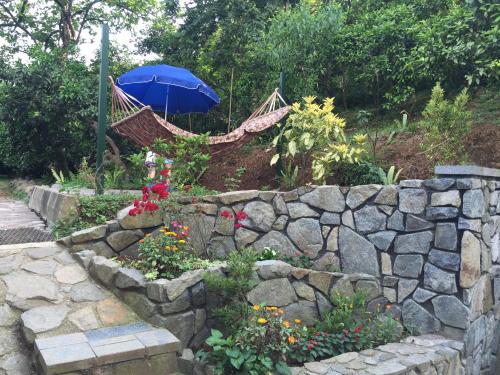 a hammock in a garden with a rock wall at Lasha Guest House in Makhinjauri
