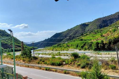 a road next to a mountain with a river at Sweet Home Aria in Çorovodë