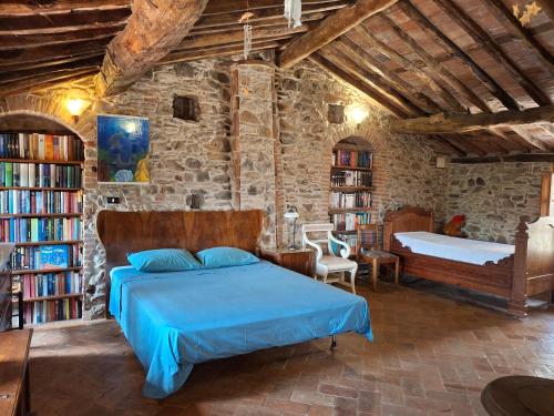 Un dormitorio con una cama azul en una pared de piedra. en Attic with balcony at Locanda del Capo, en Capannori