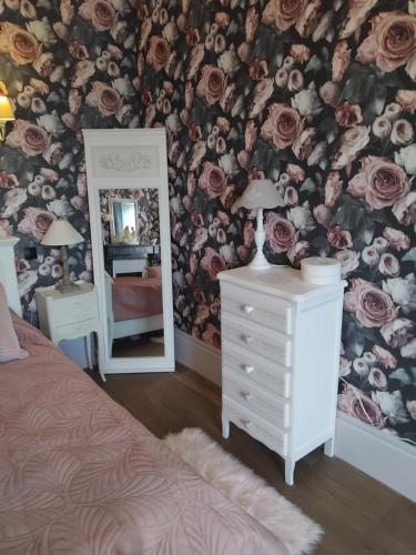 a bedroom with a floral wallpaper and a mirror at Le jardin de Kristine in Vinneuf