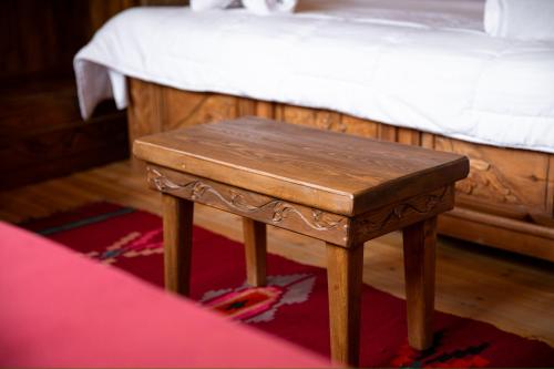 a small wooden table sitting on a rug next to a bed at Hotel Sarajet 1821 in Gjirokastër