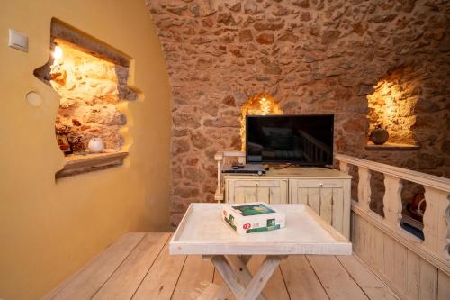 a living room with a table and a tv at Aretis Stone Retreat 