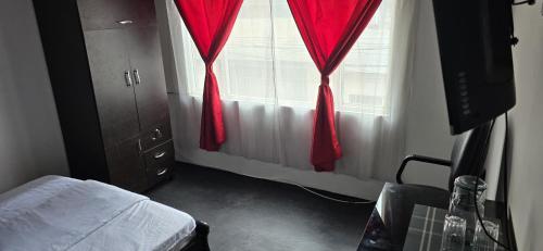 a bedroom with red curtains and a bed and a window at Hotel Migración in Bogotá