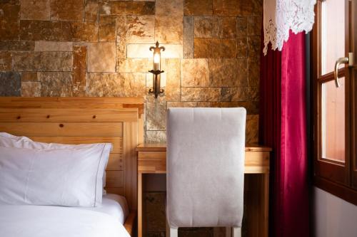 a bedroom with a bed and a desk with a chair at Hotel Sarajet 1821 in Gjirokastër