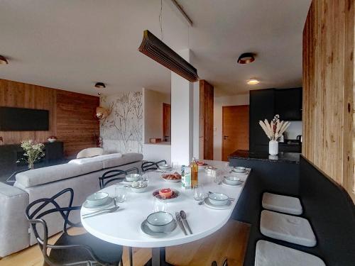 une salle à manger avec une table blanche et un canapé dans l'établissement Homency - Résidence L'Expression B31, à L'Alpe-d'Huez