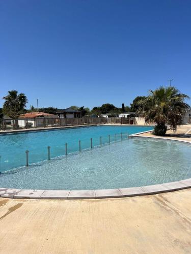 une grande piscine avec de l'eau bleue et des palmiers dans l'établissement MOBILE HOME 6 PERSONNES, à Port-la-Nouvelle