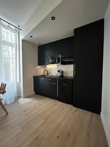 une cuisine avec des armoires noires et un plancher en bois dans l'établissement Studio élégant, à La Rochelle