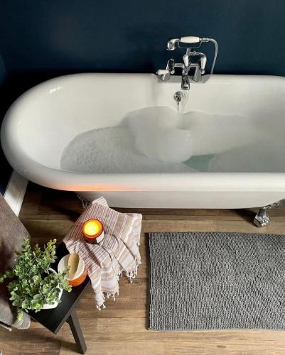 a white bath tub sitting in a bathroom at Emerson House, dog friendly with log burner close to waters edge and harbour in Poole