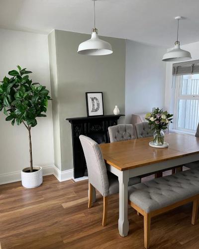 a dining room with a table and chairs and a plant at Emerson House, dog friendly with log burner close to waters edge and harbour in Poole