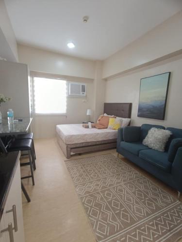 a bedroom with a bed and a blue couch at Cebu Stay Rental - Sunvida Tower Residences in Cebu City