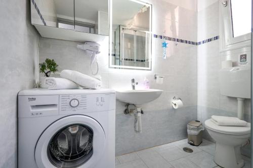 a white bathroom with a washing machine and a sink at The heart of Aegina 3 in Aegina Town