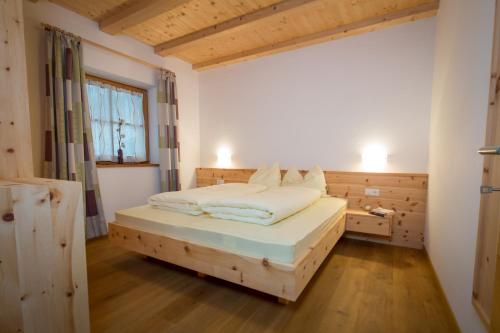 um quarto com uma cama de madeira e uma janela em Brugger Hof em Feldthurns