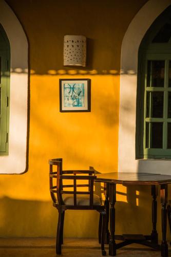 a wooden table and chair next to a yellow wall at Wildflower Villas - All Villa Hotel, Family Run in Candolim