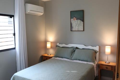 a bedroom with a bed with two lamps and a picture on the wall at A 700m da Praia e do Shopping, Liberdade, Churrasq, Garagem e Estaciona Livre in Balneário Camboriú
