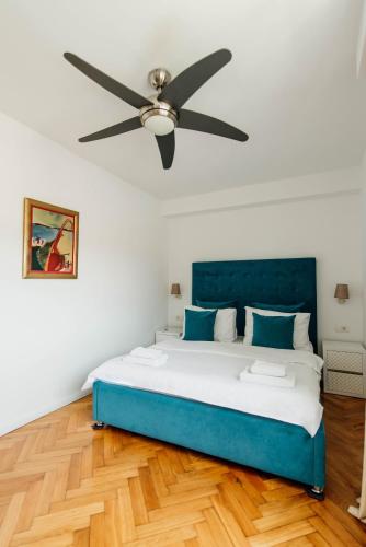 a bedroom with a blue bed and a ceiling fan at Apartments Captain's Villa in Budva
