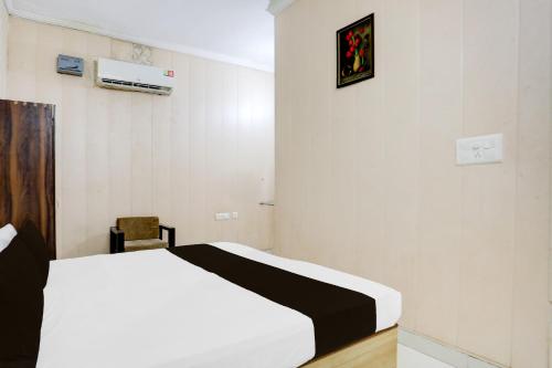 a bedroom with a white bed and a chair at SPOT ON Hotel Umang in Zirakpur