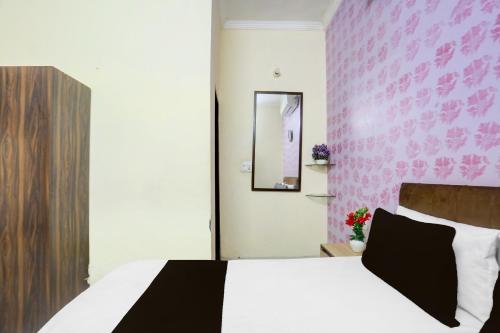 a bedroom with a white bed with a pink wall at SPOT ON Hotel Umang in Zirakpur