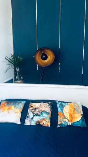 a blue wall with three pillows on a bed at Apartament Azzurro - Old Town in Kłodzko