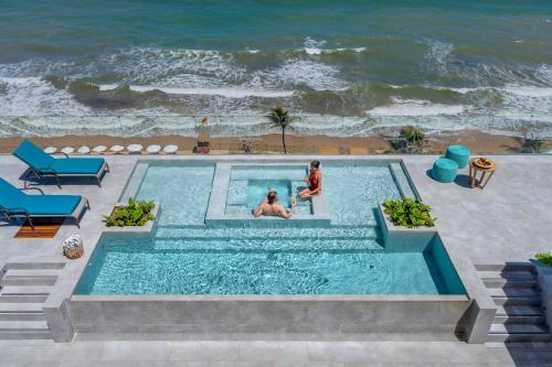 two people in a swimming pool next to the ocean at SERHS Experience Suítes in Natal