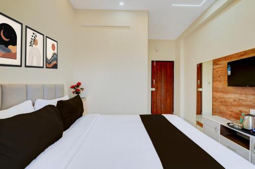 a bedroom with a large white bed and a flat screen tv at Hotel O Airport Suites in Muthugadahalli