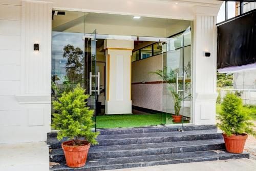 a house with glass doors and potted plants at Hotel O Airport Suites in Muthugadahalli