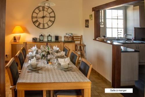 a dining room with a table and a clock on the wall at Gîte Chez Cyrille in Houffalize