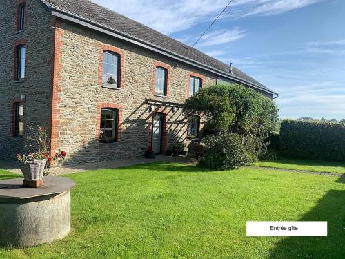 a brick house with a green lawn in front of it at Gîte Chez Cyrille in Houffalize