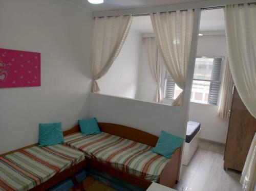 a small bedroom with two beds and a window at Kitnet aconchegante no centro, a poucos passos da praia in Praia Grande