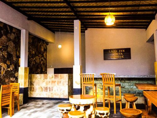 a restaurant with wooden chairs and tables in a room at Lazy Inn Kuta Lombok in Kuta Lombok