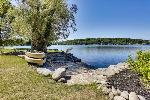a boat sitting on the grass next to a lake at Waterfront Home on White Lake Near Bethel Woods! in White Lake