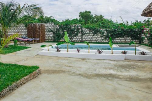 a swimming pool with plants in a backyard at Red Land House in Watamu