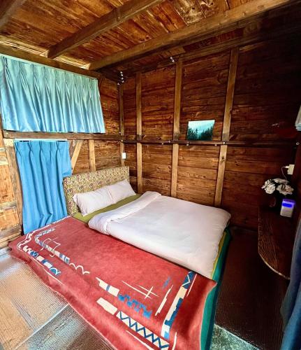 a bed in a wooden cabin with blue curtains at Nhà Tĩnh - Tiệm Cà phê Tĩnh 2 in Ấp Ða Lợi
