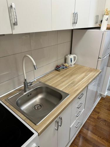 a kitchen with a stainless steel sink and white cabinets at Stan na dan Banja Luka DM in Ivišovo Greblje