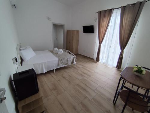a bedroom with a white bed and a wooden floor at B&B Via Roma in Sannicola