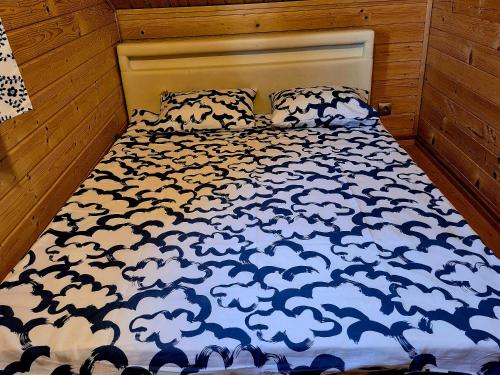 a bed with a blue and white comforter on it at Noclegi "LAS WYPAS" Trzcianka in Trzcianka