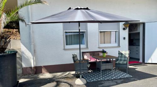a table and chairs under an umbrella in front of a house at DAS Apartment am Weinberg in Geisenheim