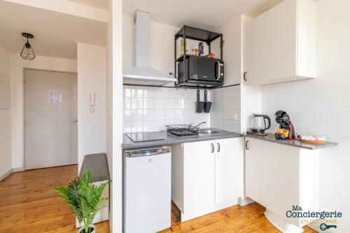 une cuisine avec des armoires blanches et un comptoir dans l'établissement Parga 41 - 500 mètres du Capitole - Hypercentre Tlse, à Toulouse