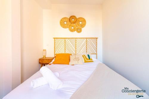 une chambre avec un lit avec des draps blancs et des oreillers jaunes dans l'établissement Charles - Hypercentre -St Sernin - Métro, à Toulouse