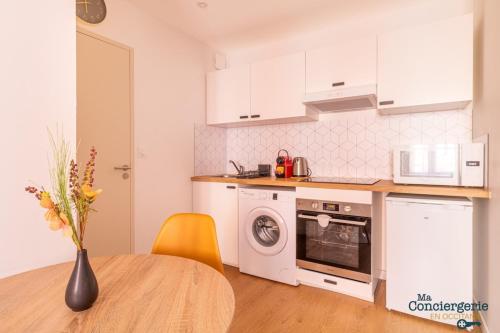 une cuisine avec des placards blancs et une table avec un vase de fleurs dans l'établissement Charles - Hypercentre -St Sernin - Métro, à Toulouse